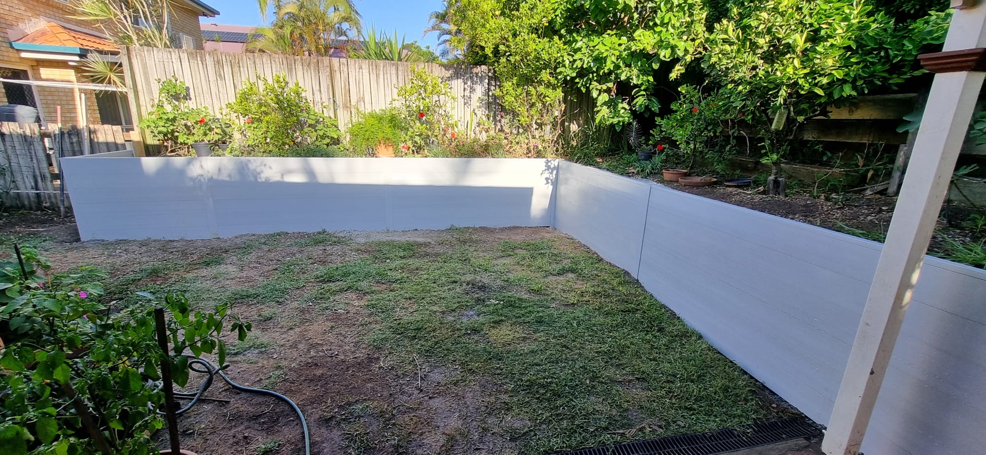 Composite timber-look retaining wall installed in a Capalaba backyard with tiered garden beds
